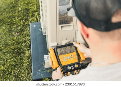 HVAC service technician checking pressures with digital gauges on a high efficiency cooling system.  - Powered by Shutterstock