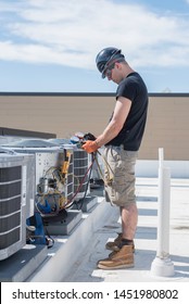 Hvac Tech Looking At His Gauges That Are Hooked Up To A Condensing Unit.