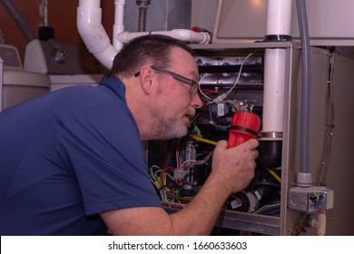 HVAC Tech Looking Over A Gas Furnace  Blue Shirt 