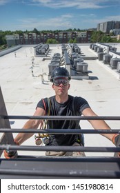 Hvac Tech On A Ladder, With Rows Of Condensers In The Background