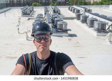 Hvac Tech On A Roof Ladder, With Condensing Units In The Background.