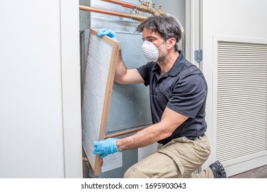 HVAC tech wearing mask and gloves changing an air filter