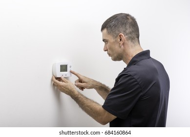 Hvac Technician Adjusting Temperature On Thermostat