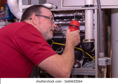 HVAC Technician Checking Out A High Efficiency Furnace  Red Shirt  