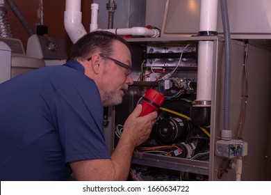 HVAC Technician Looking Over A High Efficiency Gas Furnace  Blue Shirt  