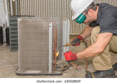 HVAC Technician Soldering A Copper Joint On A Condensing Coil Wearing Safety Gear. 