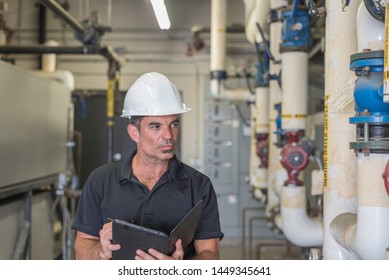 Hvac Technician With Table And Stylus, Inspecting Piping In A Boiler Room