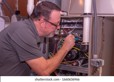 HVAC Technician Working On A High Efficiency Gas Furnace  Gray Shirt  