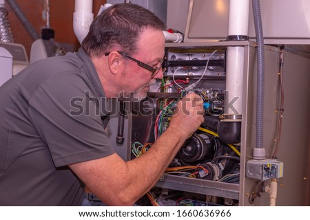 HVAC Technician Working On A High Efficiency Gas Furnace  Gray Shirt  