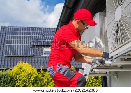 HVAC Worker Performing Heat Pump Maintenance. Device is Transferring Thermal Energy From the Outside Using the Refrigeration Cycle. Home Heating Technologies.