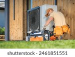 HVAC worker working on a modern heat pump outside a house.