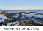 Hvitserkur rock formation standing on the icelandic coastline at sunset with a view of the snowy mountains in the distance