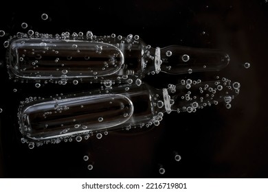 Hyaluronic Acid In Ampoules. Ampoule Beauty Products.Mesotherapy And Dermabrasion Serum In Ampoules.Cosmetic Ampoules In Bubbles In Water On A Black Background.Cosmetics Medical And Care Concept