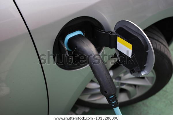 Hybrid car electric charger\
station with power supply plugged into an electric car being\
charged