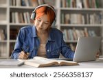 Hybrid communication. Smart young female remote class student in wireless headset attend online lecture sitting in library by notebook interact with teacher and group on distance take notes of webinar