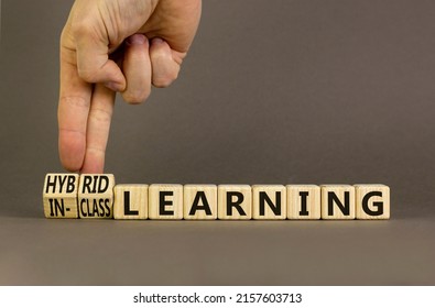 Hybrid or in-class learning symbol. Businessman turns cubes, changes words hybrid learning to in-class learning. Grey background. Education and hybrid or in-class learning concept. Copy space.