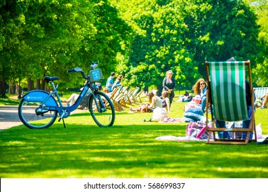 Hyde Park In London During Warm Sunny Day. People Sitting On The Grass Having Lunches. Amazing Summer Or Spring Spirit In UK. Barclays Bicycle.