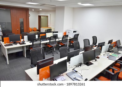 Hyderabad, India - January 19, 2021: Side View Of White And Orange Open Space Office Interior With Rows Of Computer Tables With Desktops Standing On Them