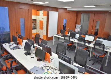 Hyderabad, India - January 21, 2021: Side View Of White And Orange Open Space Office Interior With Rows Of Computer Tables With Desktops Standing On Them