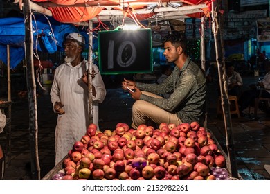 Hyderabad, India - September 2018: A Fruit Vendor Sitting Beside His Cart Full Of Apples In A Night Market In Old Hyderabad.