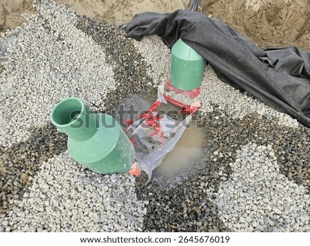 Hydrant assembly with gate valves and protective boots installed in gravel bedded trench shows water pooling; geotextile wrap visible, highlighting drainage design.