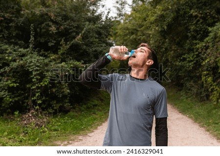 Hydration Break: A Jogger Refreshing with a Water Bottle on a Forest Trail