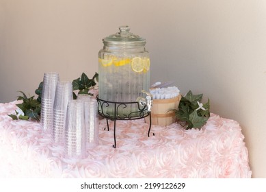 Hydration And Cooling Station For The Guests Complete With Lemon Infused Ice Water With Plastic Cups And Folding Fans To Take To Their Seats.