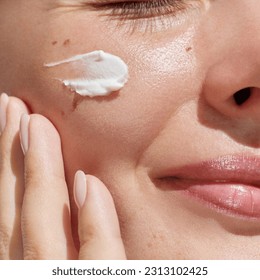 Hydration. Cream smear. Beuaty close up portrait of young woman with a healthy glowing skin is applying a skincare product. 