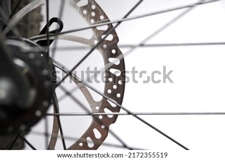 Hydraulic bicycle disk brakes, grey metal disc attached to bike wheel close up, effective popular mountain bicycle brakes. Hydraulic disk brakes on bicycle wheel, bicycle spokes gray background