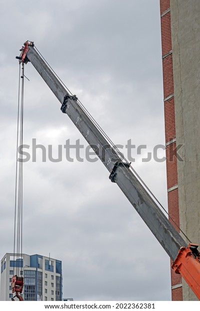 Hydraulic boom of a car crane on the background
of an urban landscape