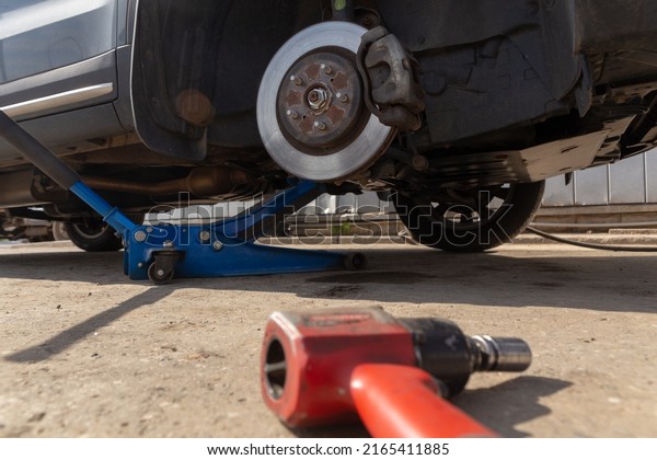 Hydraulic car jack lift the\
new car for change the tyre. Seasonal tyre change or service\
abstract concept.