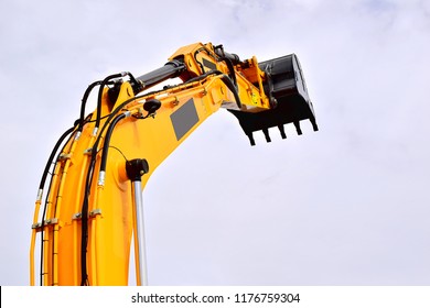 Hydraulic cylinder lifting bucket. Working equipment of a single-bucket excavator. Yellow. The background of the sky.
