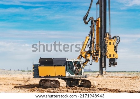 Hydraulic drilling machine at the construction site. Pile field. Modern drilling rig. The device of piles on the background of the blue sky. Work drilling rig when driving bored piles