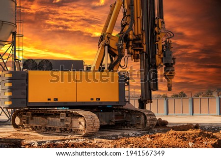 Hydraulic drilling rig against the backdrop of the sunset sky. Installation of bored piles by drilling. Foundations and foundations. Drilling in the ground