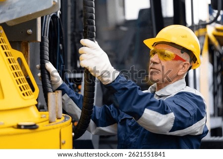Hydraulic engineer doing safety check on new installation hoses of modern drilling industrial machine.