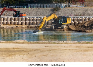 Hydraulic excavator scooping sediment from the riverbed