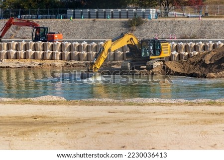 Hydraulic excavator scooping sediment from the riverbed
