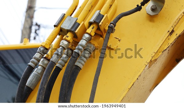 Hydraulic hoses and couplings on the mechanical\
arm of the machine are yellow. Old coupling of hydraulic powertrain\
close-up.