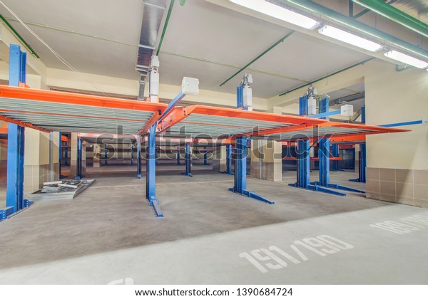 Hydraulic lift or\
mechanical jack for repair and storage of car in underground\
parking. Modern underground parking without cars. Signs and boards\
indicating\
directions.