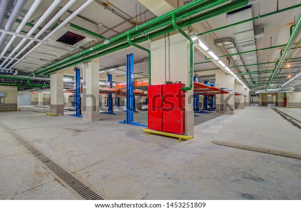 Hydraulic lift or mechanical jack for repair and\
storage of car in underground parking. Modern underground parking\
without cars. Signs and boards indicating directions. Service\
station