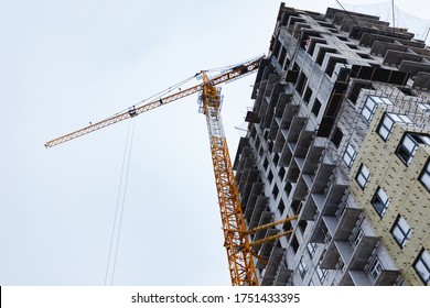 Hydraulic Luffing Jib Tower Cranes And Workers Being Poured Concrete Into Foundation. Cement Pouring Into Formwork Of Building At Construction Site. Tower Cranes Constructing A New Residential Build