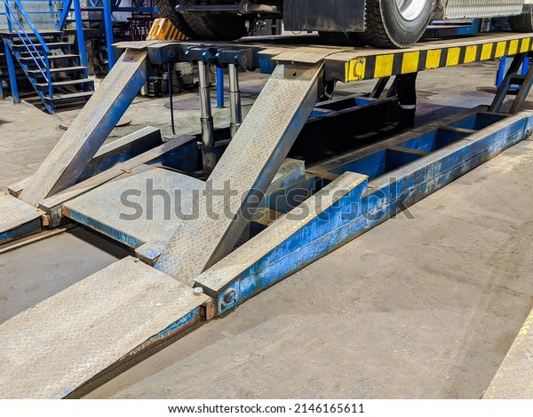 A hydraulic platform for lift cargo\
truck. Lifting the car on the platform. Close\
up.