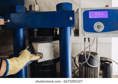 Hydraulic press machine testing compression strength of concrete cube sample in material testing laboratory, determining its resistance to compression stress