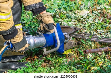 Hydraulic Scissors For Emergency Rescue Operations. Equipment For Rescue Operations. Manual Mechanized Tool. A Firefighter Cuts Metal Bars With Hydraulic Scissors.