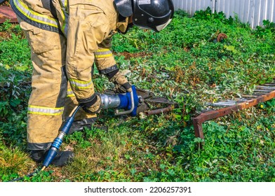 Hydraulic Scissors For Emergency Rescue Operations. Equipment For Rescue Operations. Manual Mechanized Tool. A Firefighter In Special Protective Clothing Cuts Metal Bars With Hydraulic Scissors .