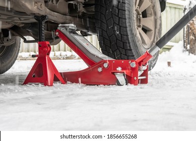 Hydraulic Trolley Jack Car Lift and Jack stand for changing car wheels. Replacing wheel in winter on snowy road in snowfall.
