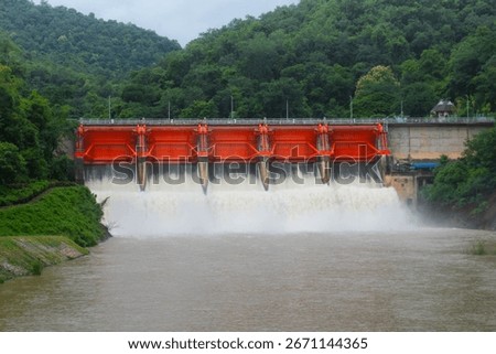 Hydro dam structure with open gates releasing muddy flood water.