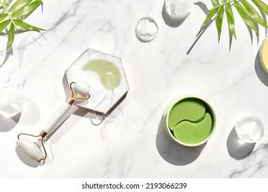 Hydrogel Pads And Chinese Stone Roller On Off White Marble Stone Background, Palm Leaf. Direct Sunlight, Long Shadows. Eye Patch, Skincare Beauty Treatment At Home. Part Of Skin Daily Care Routine.