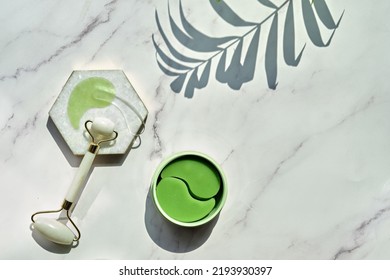 Hydrogel Pads And Chinese Stone Roller On Off White Marble Stone Background, Palm Leaf. Direct Sunlight, Long Shadows. Eye Patch, Skincare Beauty Treatment At Home. Part Of Skin Daily Care Routine.