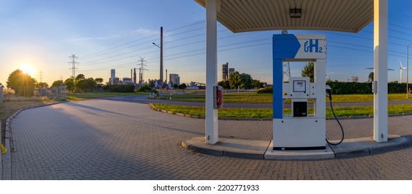 Hydrogen Fuel Pump For Automobiles Running On Pollution-free Hydrogen-powered Fuel Cells. Self Service Hydrogen Filling Station With Oil Refinery On The Background